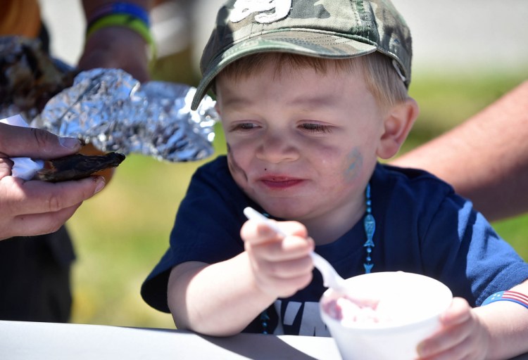 Austin Hood, 2, grimaces after taking a bite out of a smoked alewife at the annual Benton Alewife Festival at Family Fun Park in Benton on Saturday.