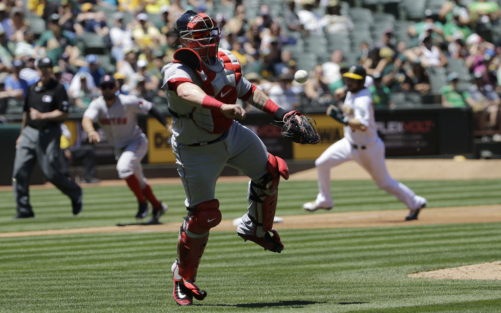 Boston catcher Christian Vazquez makes a throwing error, allowing Oakland's Trevor Plouffe to score a run during the second inning of Saturday's game in Oakland, Calif. Oakland won the game, 8-3. (Associated Press/Jeff Chiu)