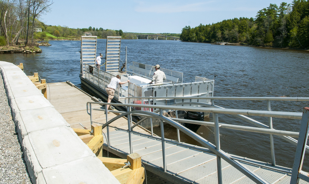 Swan Island staffers push the ferry off from the new dock on the shore of the Kennebec River in Richmond.