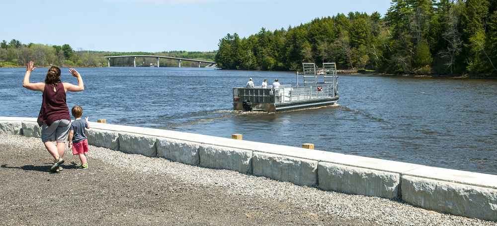 Lyman residents Liz Dunn and her son Spencer, 3, wave to the operators of the Swan Island ferry from the recently renovated boat launch area along the Kennebec River in Richmond. Dunn and Spencer had just returned from a visit to the island.