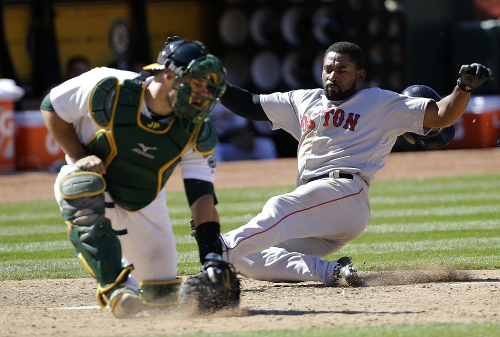 Jackie Bradley Jr. slides safely into home as Oakland catcher Josh Phegley fields the throw in the ninth inning of Boston's 12-3 win Sunday.