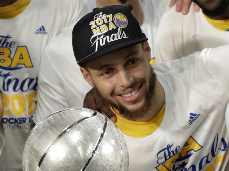 The Warriors' Stephen Curry poses by the trophy after Golden State beat the Spurs 129-115 Monday to finish a sweep of the West finals.