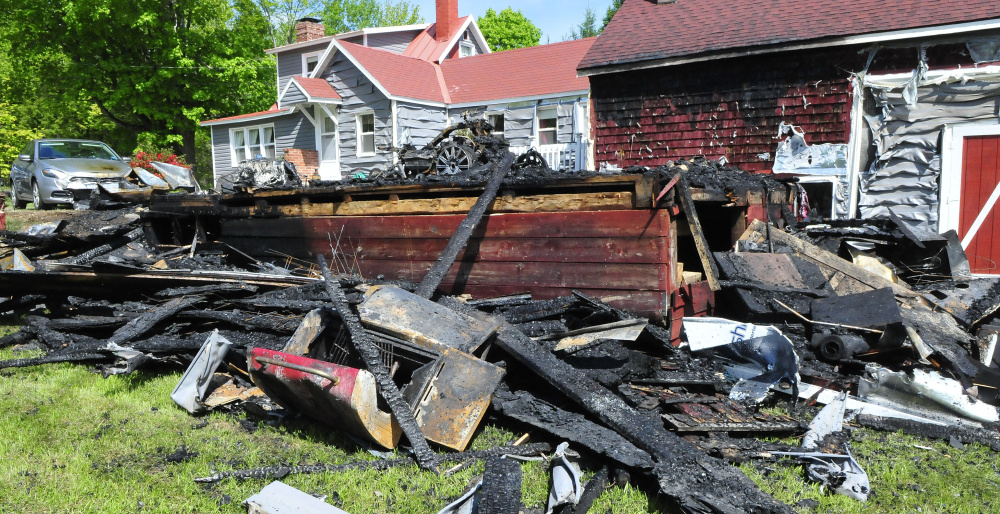 A propane cooking grill, foreground, lies in a pile of burned debris Tuesday from a garage that burned Monday evening at the David McKeage residence on the Bellsqueeze Road in Clinton. A car, truck and new siding on a nearby barn were damaged and a three-wheel motorcycle was destroyed after a passerby spotted smoke and flames shortly after McKeage had finished grilling dinner.