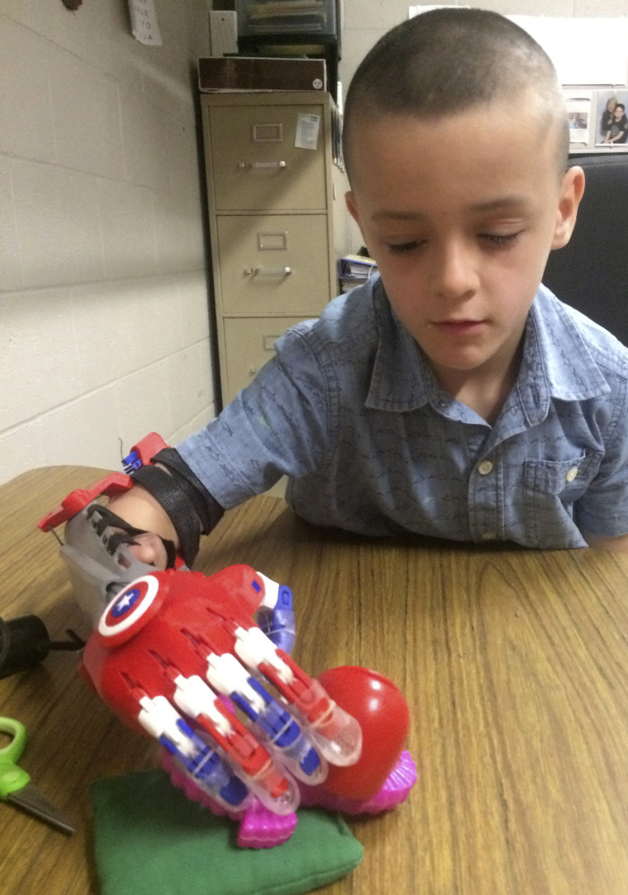 Harun Halilovic, a second grader in Bedford, N.H., grabs an object with a prosthetic arm 3-D printed for him by students at the Academy for Science and Design in Nashua, N.H. He hopes to be able to catch a ball and ride a bike.