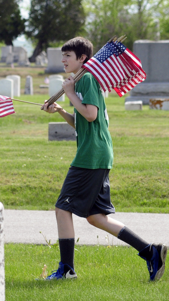 Colin Dalton searches for a veteran's grave in Augusta. Whitefield students placed flags in the section near the Augusta State Airport.