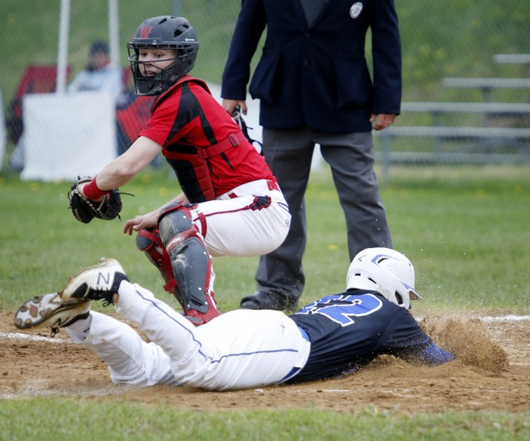 Colin Coyne of Falmouth dives across the plate to score a run in the third inning Thursday as Wells catcher Michael Wrigley fields the late throw. Falmouth won, 5-4.