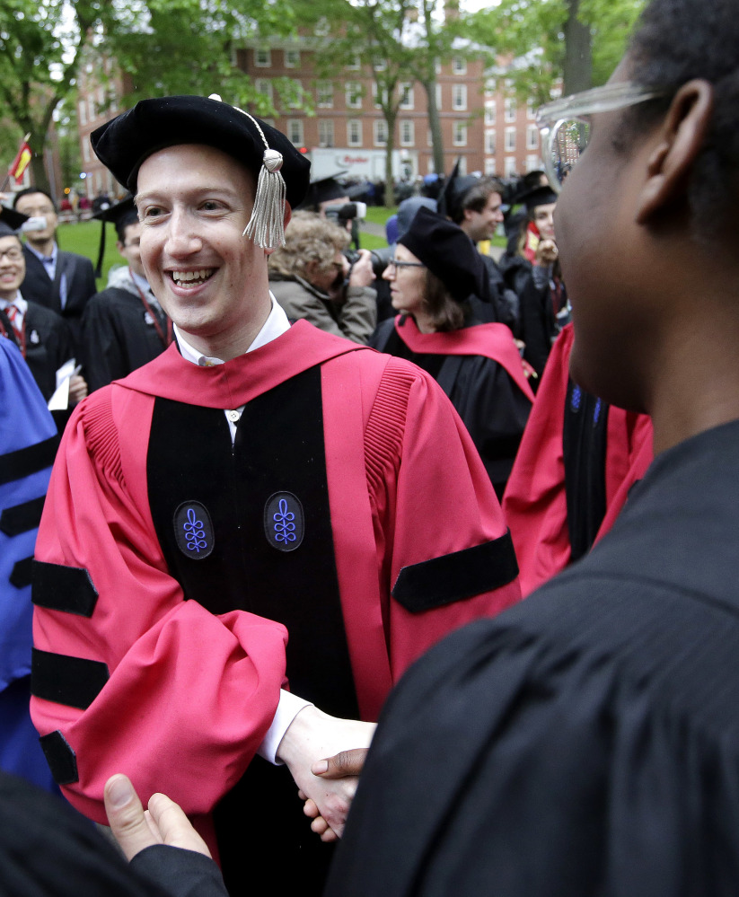 Facebook CEO and Harvard dropout Mark Zuckerberg greets graduating students as he walks in a procession though Harvard Yard.