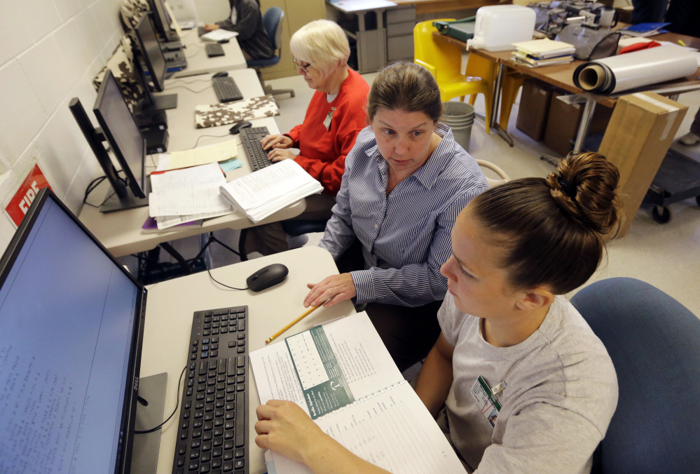 Inmates Linda Ellis, left, and Molly Martel, right, use computers Monday as they receive instruction from Nancy Wittmershaus, center, at the New Hampshire Correctional Facility for Women in Goffstown, N.H. The women are participating in an innovative program to learn how to translate books into Braille.