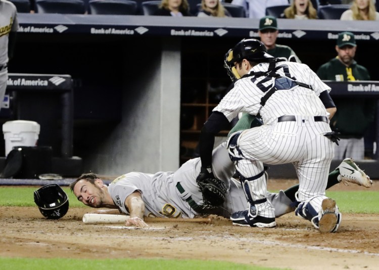 Catcher Austin Romine of the New York Yankees tags out Adam Rosales of the Oakland Athletics during the eighth inning of Oakland's 4-1 victory Friday night at Yankee Stadium.