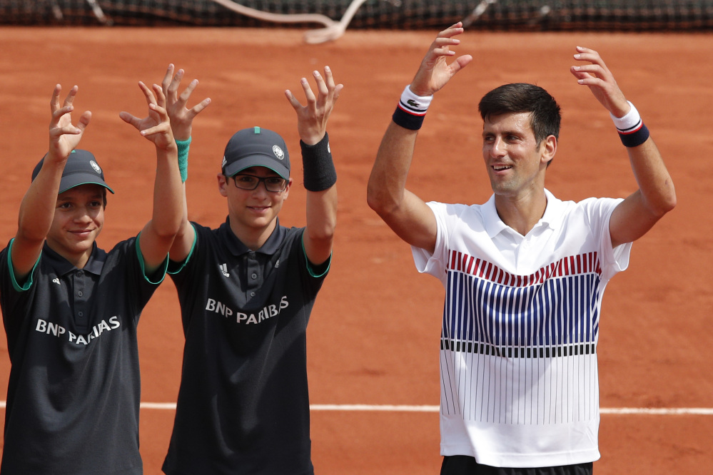 Defending French Open champion Novak Djokovic celebrates with a couple of ball boys after his 6-3, 6-4, 6-2 win over Marcel Granollers in a first-round match Monday.