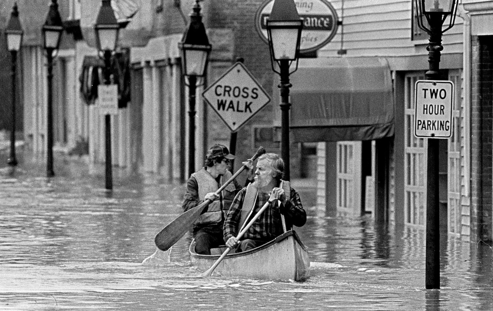 Sumner "Sam" Webber, left, and John Jacques paddle a canoe on Water Street just past Central Street after the Kennebec River flooded downtown Hallowell in 1987.