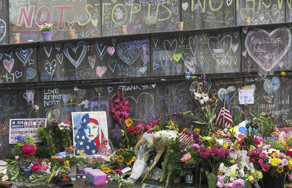 Flowers, candles and chalk tributes are seen on Tuesday, May 30, 2017, covering a memorial to two men who were fatally stabbed after shielding two young women from an anti-Muslim tirade on a Portland, Ore., light-rail train. Jeremy Joseph Christian, 35, made a first court appearance on charges of aggravated murder and attempted murder Tuesday in a Portland, Oregon courthouse. (AP Photo/Gillian Flaccus)