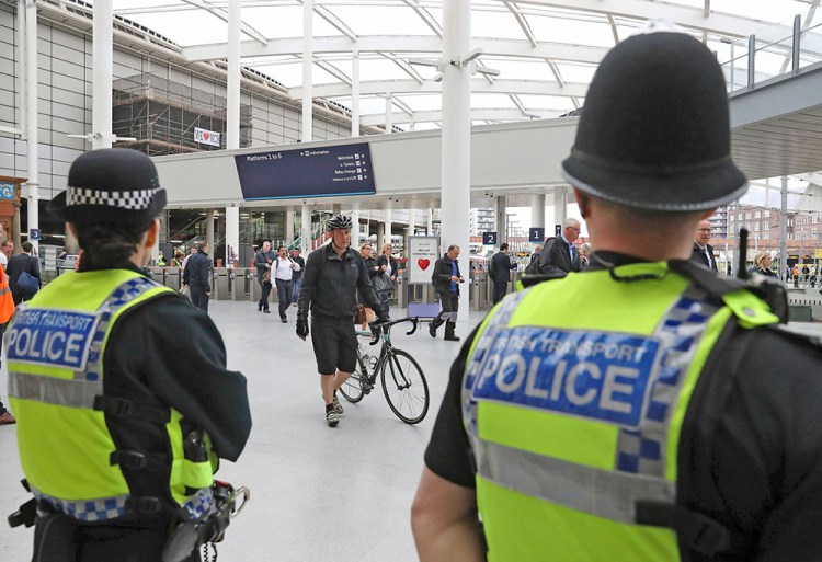 Police watch as commuters pass through Manchester Victoria railway station, which has reopened for the first time since the terror attack on the adjacent Manchester Arena that killed more than 20 people. 