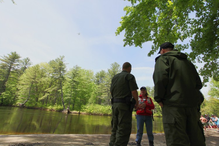 Yvette Lizotte of the American Red Cross talks with game wardens at the Walker's Falls Campground during the search for a missing woman on the Saco River in Fryeburg on May 28. A Fryeburg officer who was injured during the search has died.
