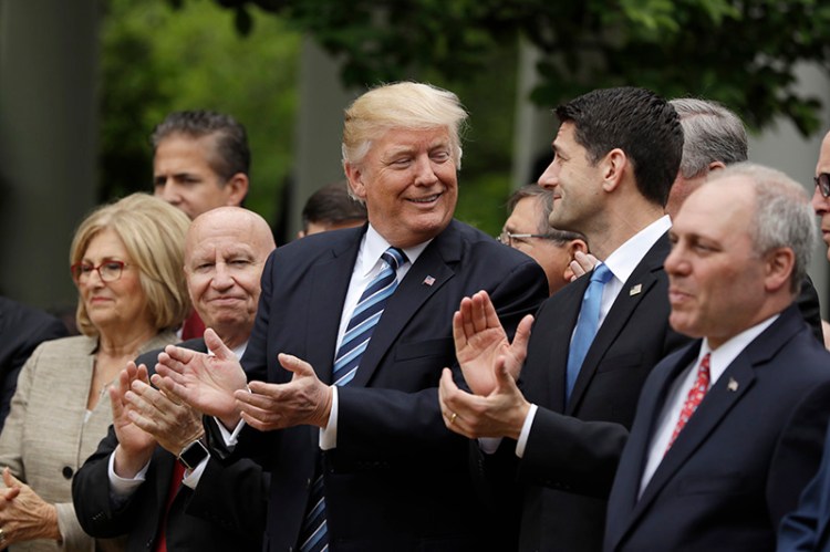 President Donald Trump, flanked by House Ways and Means Committee Chairman Rep. Kevin Brady, R-Texas, and House Speaker Paul Ryan of Wis. applaud in the Rose Garden of the White House after the passage of the health care bill. 