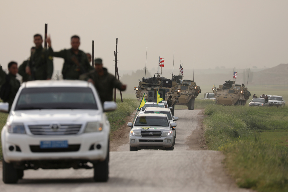 Kurdish fighters from the People's Protection Units head a convoy of U.S military vehicles in the town of Darbasiya, next to the Turkish border in Syria, in April.