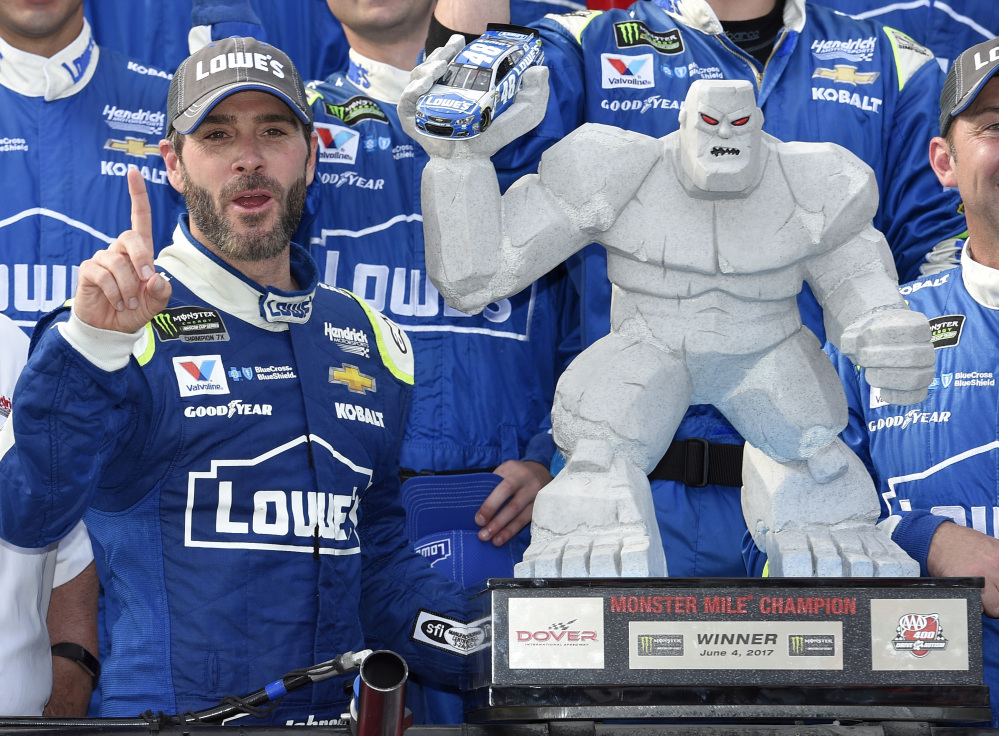 Jimmie Johnson, left, poses with the trophy in Victory Lane after he won a NASCAR Cup series race Sunday at Dover International Speedway.