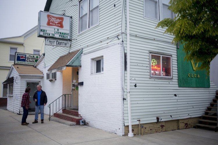 Customers smoke last Wednesday outside the Griffin Club in South Portland during its last night of business. Penny Prior and Ginger Cote of Cape Elizabeth have bought the building.