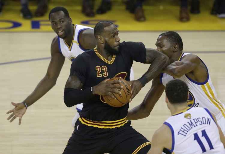 Cleveland Cavaliers forward LeBron James (23) shoots between Golden State Warriors forward Draymond Green, top, guard Klay Thompson (11) and forward Kevin Durant during the first half of Game 2 of basketball's NBA Finals in Oakland, Calif., on Sunday.
