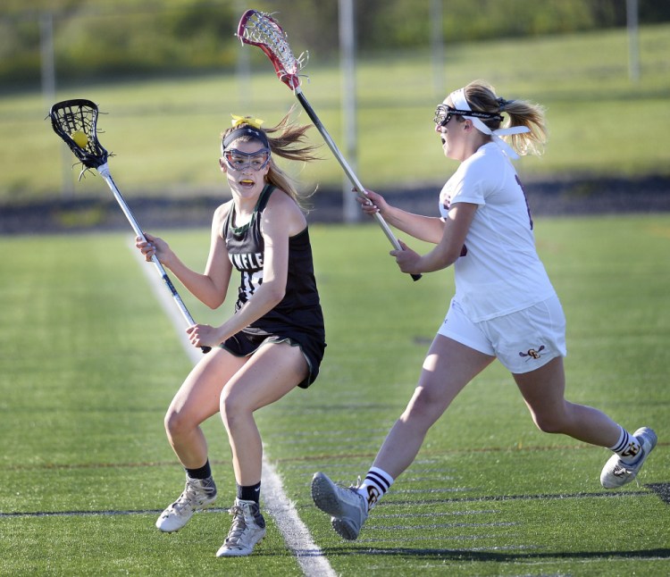 LZ Olney of Waynflete looks for an open teammate as Caroline Coburn of Cape Elizabeth pursues Wednesday night during the Capers' 10-6 victory in a Class B South girls' lacrosse quarterfinal. Cape will be at top-ranked Kennebunk in a semifinal Saturday.