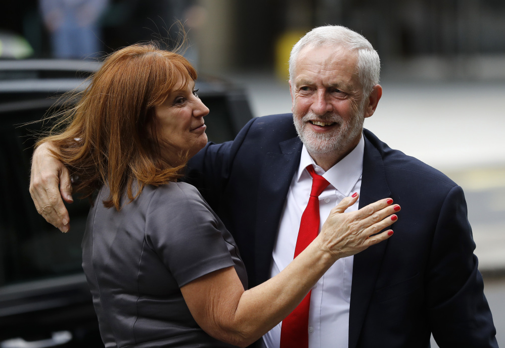 Britain's Labour party leader Jeremy Corbyn is greeted as he arrives at Labour party headquarters in London on Friday, the day after national elections that gave Labour more seats in Parliament.