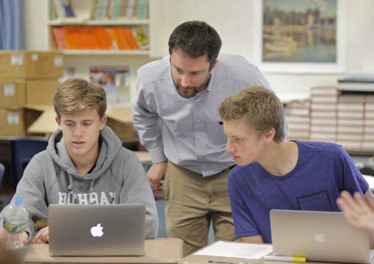 Teacher William Putnam talks with students Hunter Brown, left, and Benjamin Ingalls in a ninth-grade honors English class at Gray-New Gloucester High School. Putnam has adopted the philosophy behind proficiency-based education and practices it in his classes.