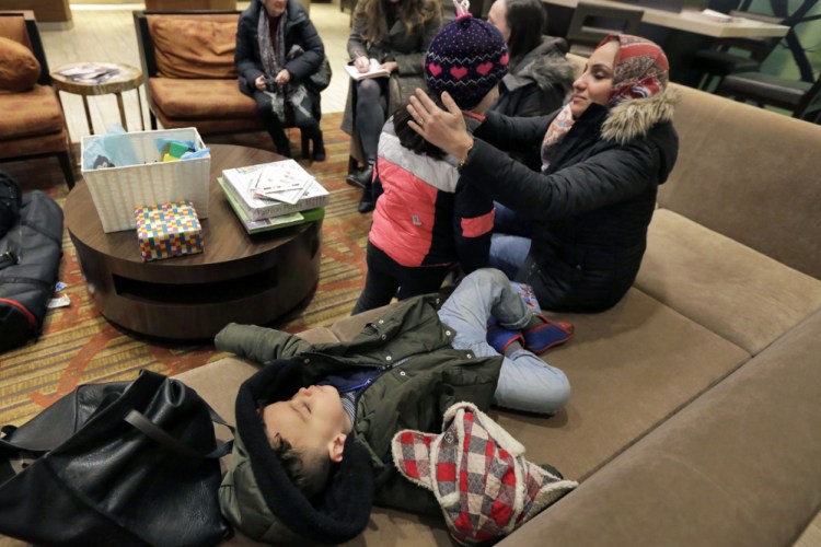Hiba Alaskry, wife of Munther Alaskry, talks with their daughter Dima as their son Hassan naps on a couch in the lobby of their New York hotel in February. The family arrived at New York's Kennedy Airport after the Trump administration reversed course and said Munther Alaskry and other interpreters who supported the U.S. military could come to America. They spent nearly a week in limbo in Baghdad, thinking their hopes of starting a new life free from death threats had been shattered.