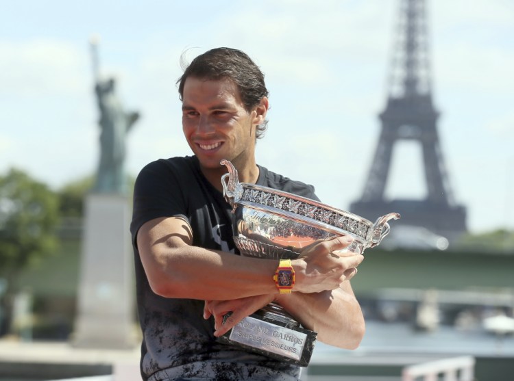 Spain's Rafael Nadal poses for photos with his French Open trophy aboard a barge cruising on the Seine river in Paris on Monday.