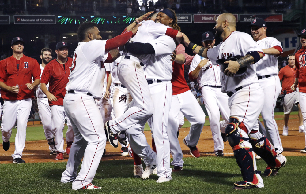 Dustin Pedroia is lifted by Hanley Ramirez after his game-winning RBI single in the 11th inning of Monday night's game against the Philadelphia Phillies.