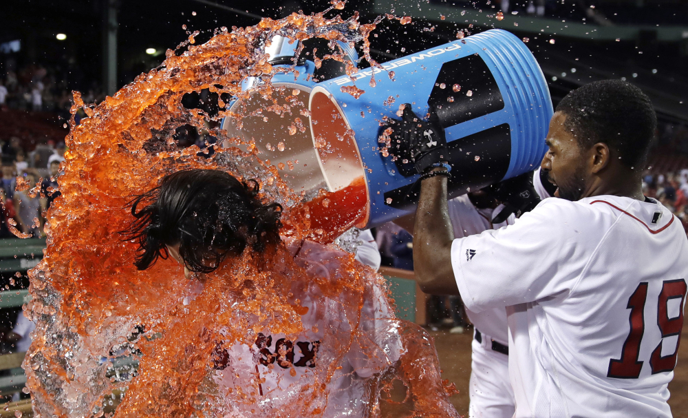 Boston's Andrew Benintendi is doused by Jackie Bradley Jr. and others after his game-winning RBI single in the bottom of the 12th inning against the Philadelphia Phillies at Fenway Park on Tuesday. The Red Sox won 4-3.