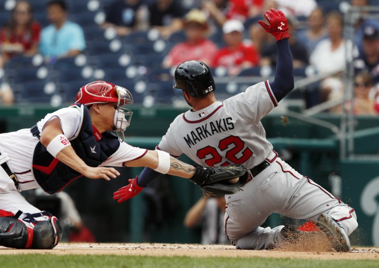 Nick Markakis of the Braves slides safely into home on a single by Matt Adams as Nationals catcher Jose Lobaton reaches with a late tag during the first inning of Atlanta's 13-2 win Wednesday.