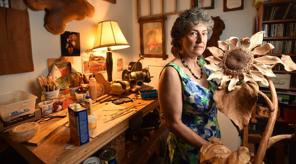 Canton artist Laurie Sproul with a wood sunflower in her home studio. Sproul and a Winslow-based artist are hoping their work helps lobbyists' effort to persuade Congress to act on climate change.