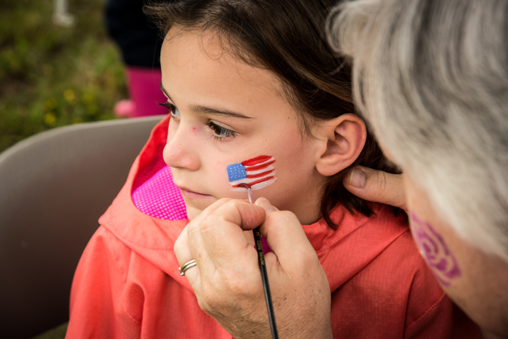 Vanessa Tyler, 6, of Augusta gets a flag painted on her face Saturday during Kennebec River Day at Mill Park in Augusta.