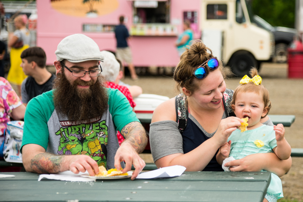 The Hamner family enjoys fried dough with lemon sauce Saturday during Kennebec River Day at Mill Park in Augusta. From left are Bryan, Loni and their daughter, 1-year-old Violet.