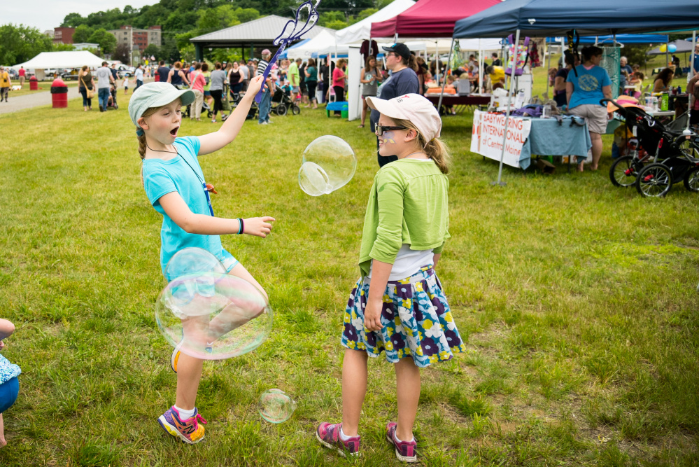 Alana, 8, left, and Sabine LaCourse, both of Boothbay, play with bubbles Saturday during Kennebec River Day at Mill Park in Augusta. The festival moved from Capitol Park to the river venue this year.