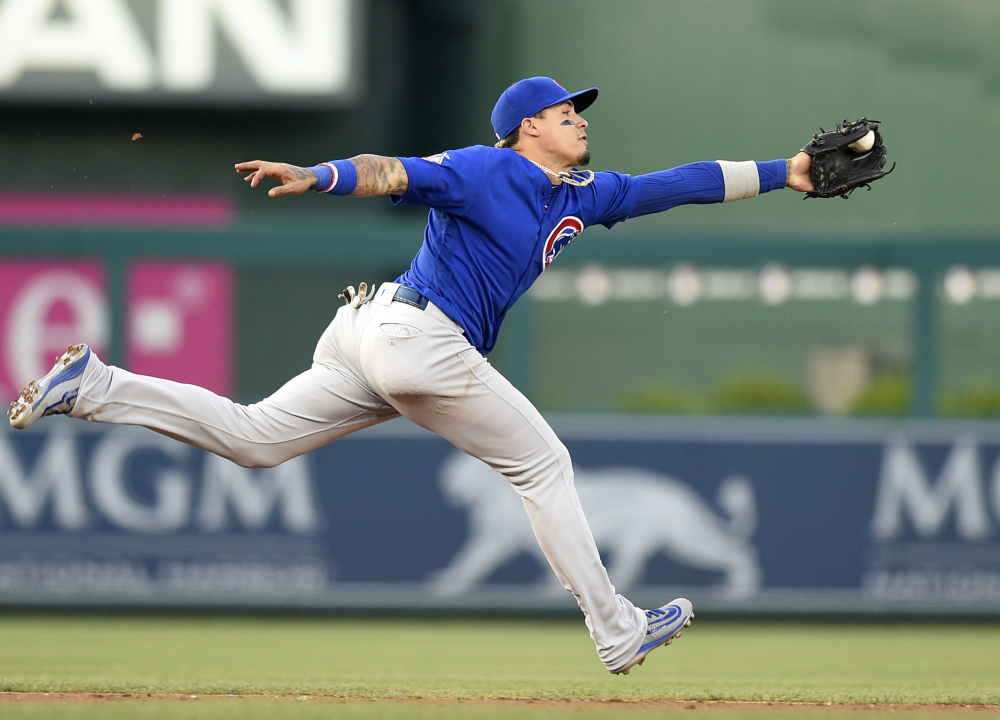 Cubs shortstop Javier Baez lunges for a ball hit by Trea Turner of the Nationals, but not in time to throw out Turner at first base. The Cubs survived Washington's four-run rally in the ninth, holding on for a 5-4 win.
