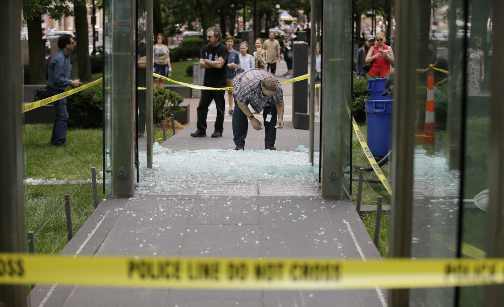 Spectators gather as Bob Satterlund, facilities manager for Combined Jewish Philanthropies of Boston, begins to pick up broken glass from one of the New England Holocaust Memorial's glass panels Wednesday.
