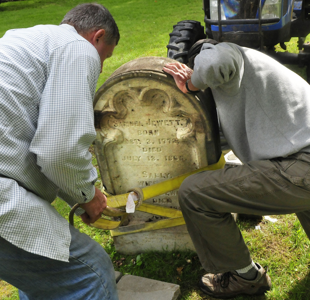 It took a few tries to align the stone on the grave pedestal as Hank McIntyre, left, and Logan Johnston strap the heavy stone.