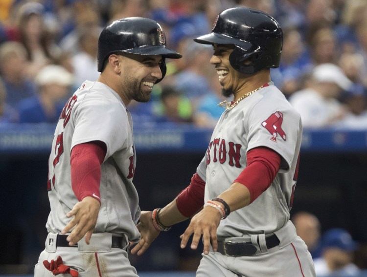 Boston's Mookie Betts, right, celebrates with Deven Marrero after scoring on a Dustin Pedroia double in the fifth inning Friday night against the Blue Jays at Toronto.