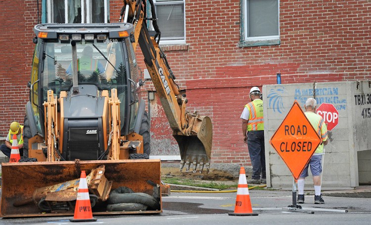 Crews work to restore a water main break at the corner of State and York streets in Portland Friday. 