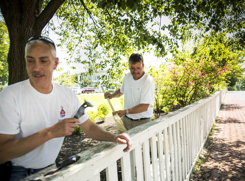 Painters Jeff Gregoire, left, of Augusta and Ted Brown, of West Gardiner, work in the shade as they scrape and paint the fence at the Blaine House in Augusta on Monday. Temperatures were expected to reach into the 90s, prompting Augusta elementary schools to let students go home early.