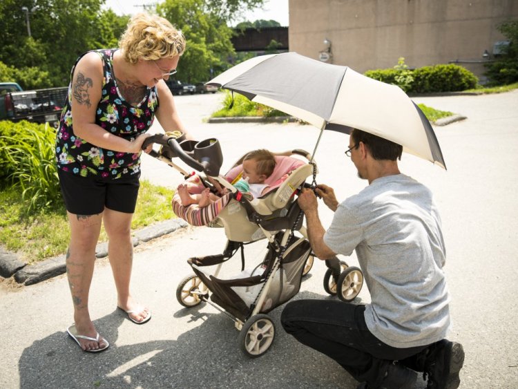 Parents Nicole and Joe Carter, of Augusta, adjust an umbrella and stroller in an effort to keep their 8 month old daughter Persephone shaded and cool as they walk down Water Street in Augusta on Monday.
