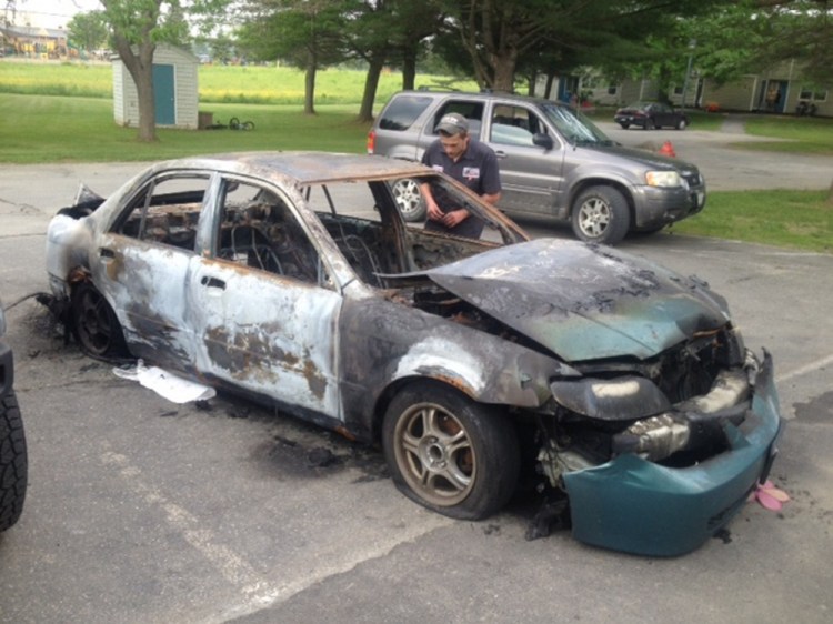 Quincy McLaughlin of Family Circle in Skowhegan looks over his 2001 Mazda Protégé that was consumed by fire early Monday. He said authorities suspect arson.