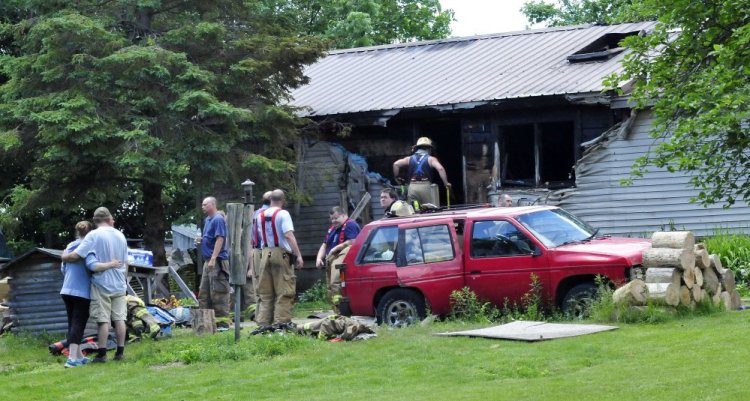 Firefighters from several area departments battled a fire that destroyed a home Thursday on Higgins road in Pittsfield. Homeowner Tyler Bishop, second from left, is comforted by a woman.