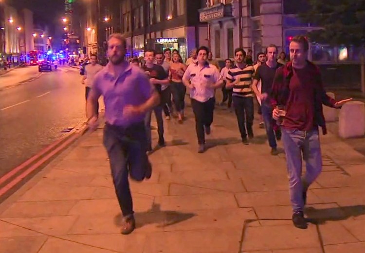 In this image taken from video footage, people run from the scene of attack, alongside a man strolling holding a pint of beer, right. People in the U.K. have responded to the deadly London Bridge attack with sorrow and distinctly British humor, hailing the man with the pint as a tongue-in-cheek symbol of defiance.