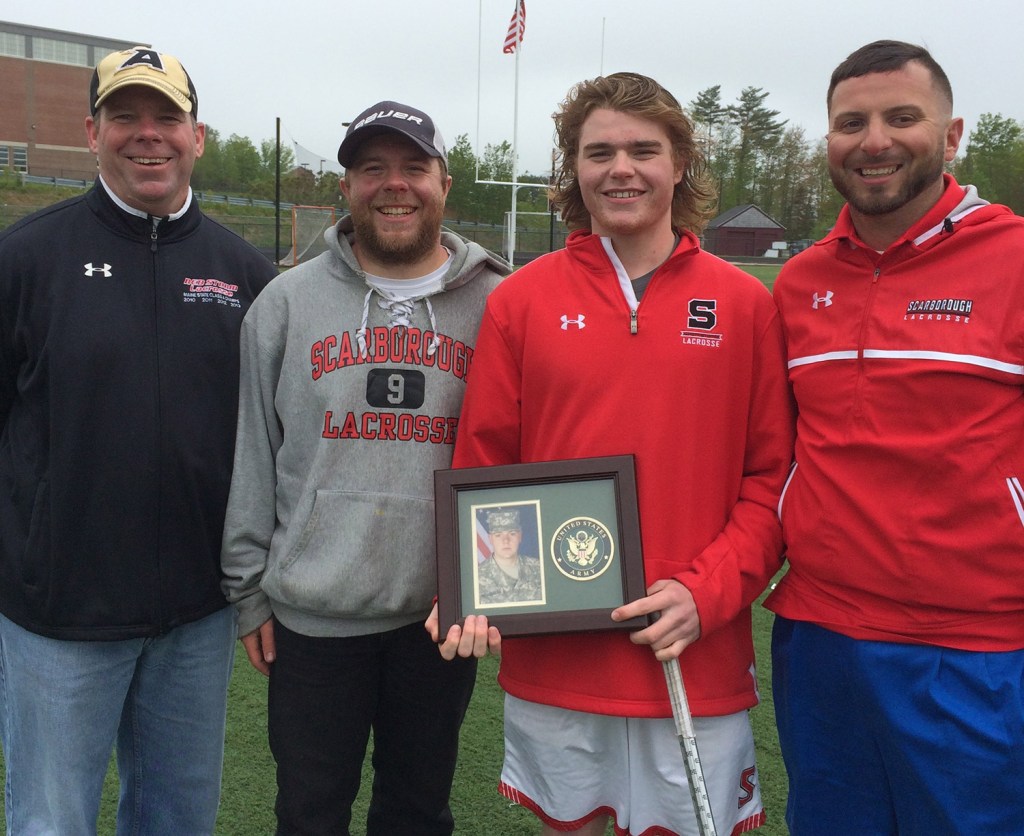 Sam Neugebauer, second from right, has been the leading scorer on the Scarborough boys' lacrosse team for the past two years. He completes a line of three Neugebauer brothers who have been in the program for 11 straight seasons. After the team's final regular season game, he posed with, from left, his father, Kyle, oldest brother Nick and Coach Joe Hezlep while holding a picture of middle brother Ben Neugebauer, who is stationed in Texas in the Army.