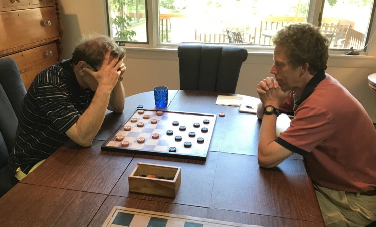 Six-time defending New England checkers champion Joseph Margolin holds his head in concentration against tournament newcomer Glenn Jordan. 