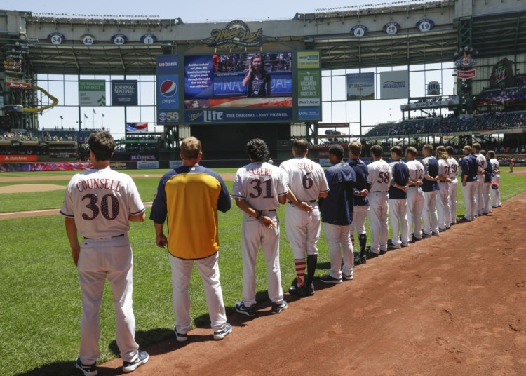Milwaukee Brewers players line up for the national anthem before Monday's game against the Baltimore Orioles, in a baseball tradition that's in its 100th season.