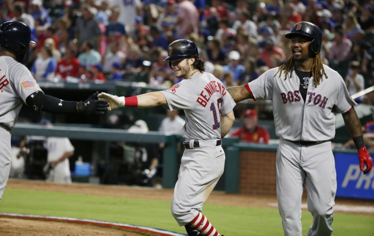 Boston Red Sox left fielder Andrew Benintendi, center, is congratulated by teammates Jackie Bradley Jr., left, and Hanley Ramirez on his three-run home run against the Texas Rangers during the fifth inning Tuesday in Arlington, Texas.