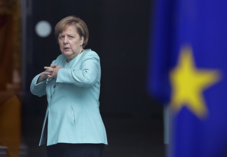 German Chancellor Angela Merkel stands behind a European flag as she waits for the arrival of Chinese President Xi Jinping at the chancellery in Berlin on Wednesday.